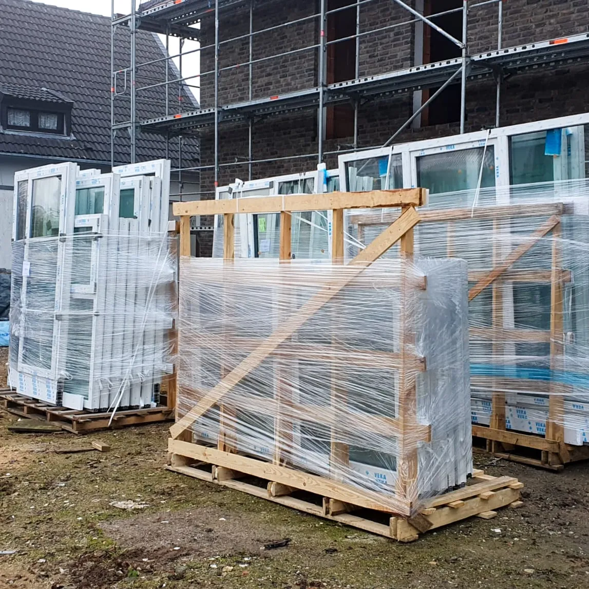 Verpackte Fensterelemente auf Paletten vor einem Gebäude