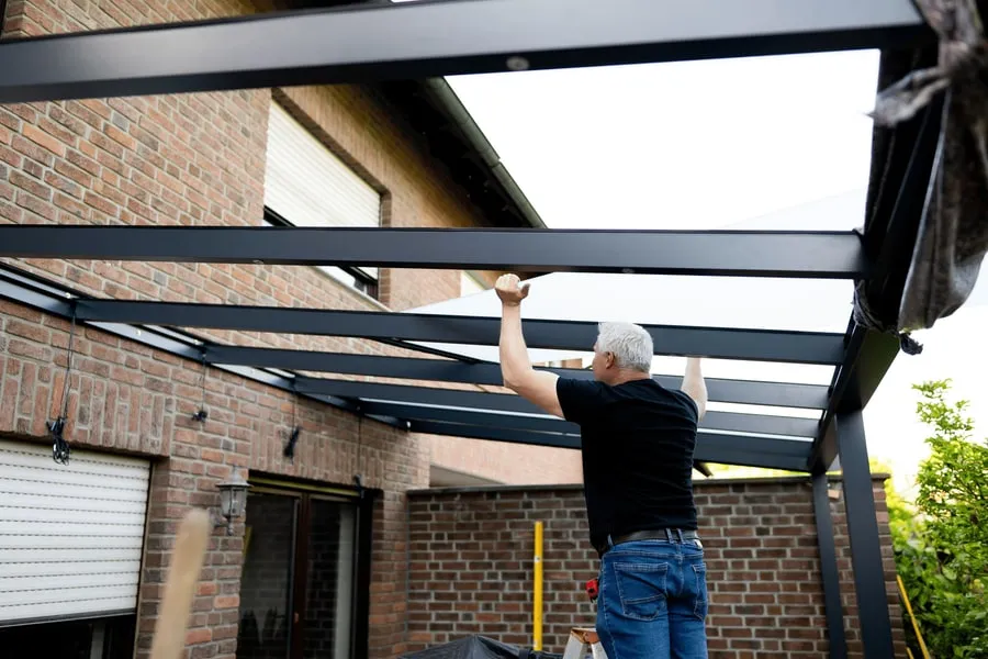 Monteur bei der Montage eines Terrassen-Vordachs